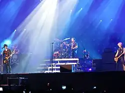 A color photograph of members of the group Green Day on stage with instruments